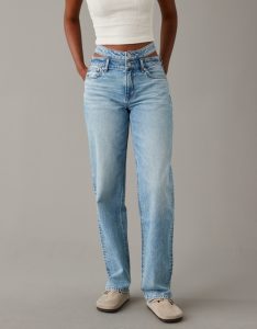 A waist down shot of a woman waring white top with blue baggy jeans