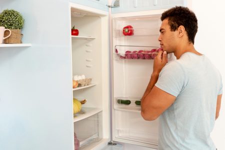Young man looking inside a fridge